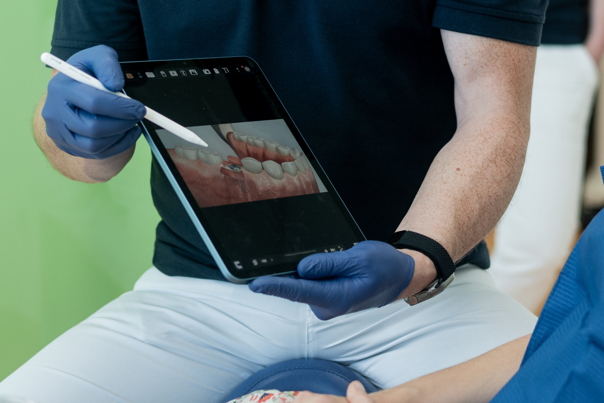 Zahnarzt zeigt einer Patientin ein digitales 3D-Modell ihres Gebisses auf einem Tablet